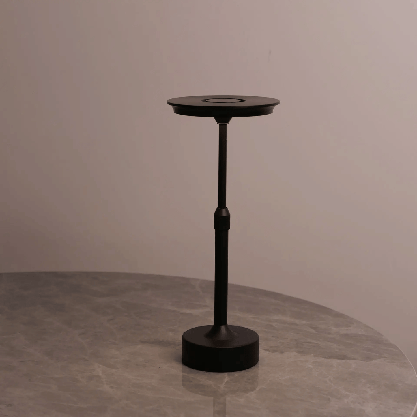 Black adjustable stand on a gray surface with a neutral background
