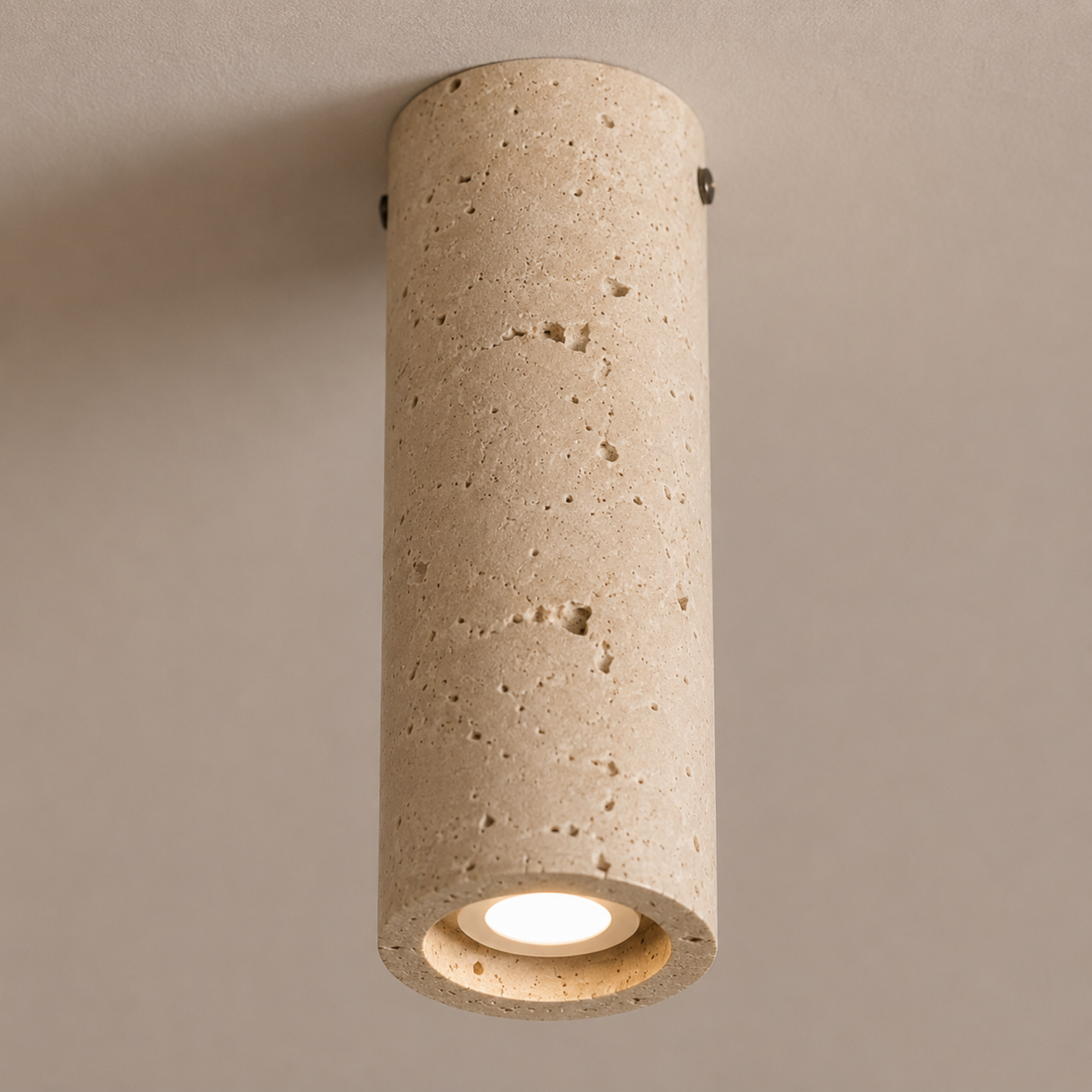 Cylindrical concrete ceiling light fixture on a beige wall.
