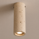 Cylindrical concrete ceiling light fixture on a beige wall.