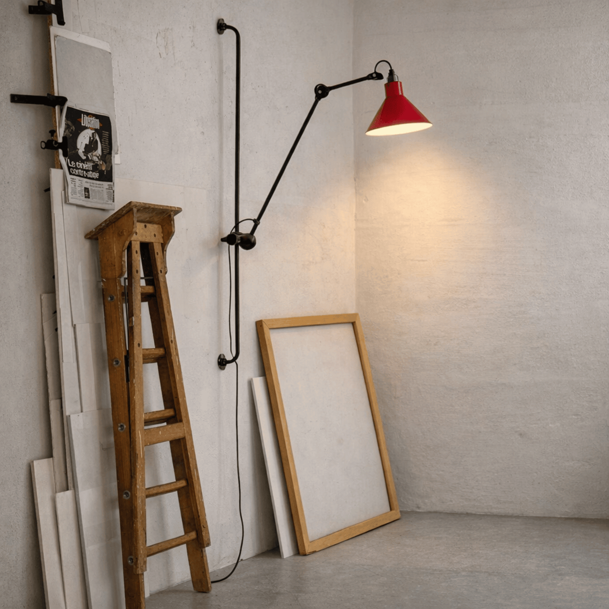 Wooden ladder, framed mirror, and wall-mounted lamp with red shade in a room.