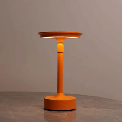 Orange floor lamp with a round base and cylindrical shaft on a gray surface.