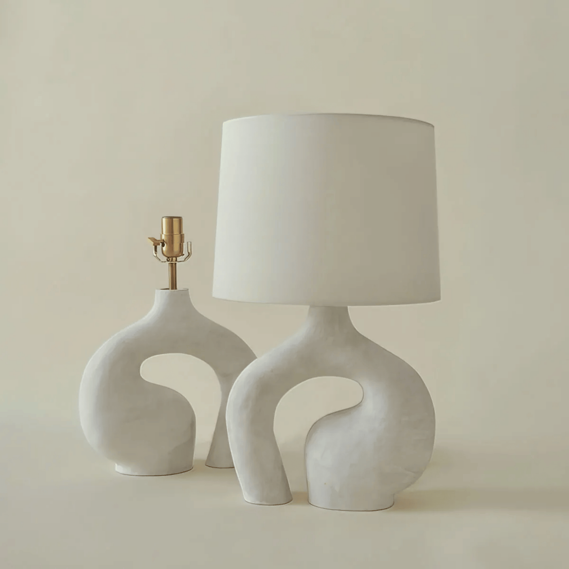 Two ceramic table lamps with unique designs on a plain background
