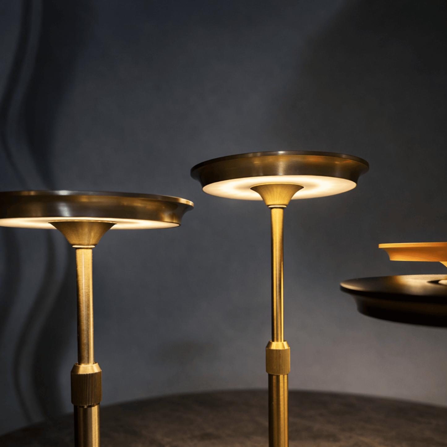 Three gold candle holders against a dark background