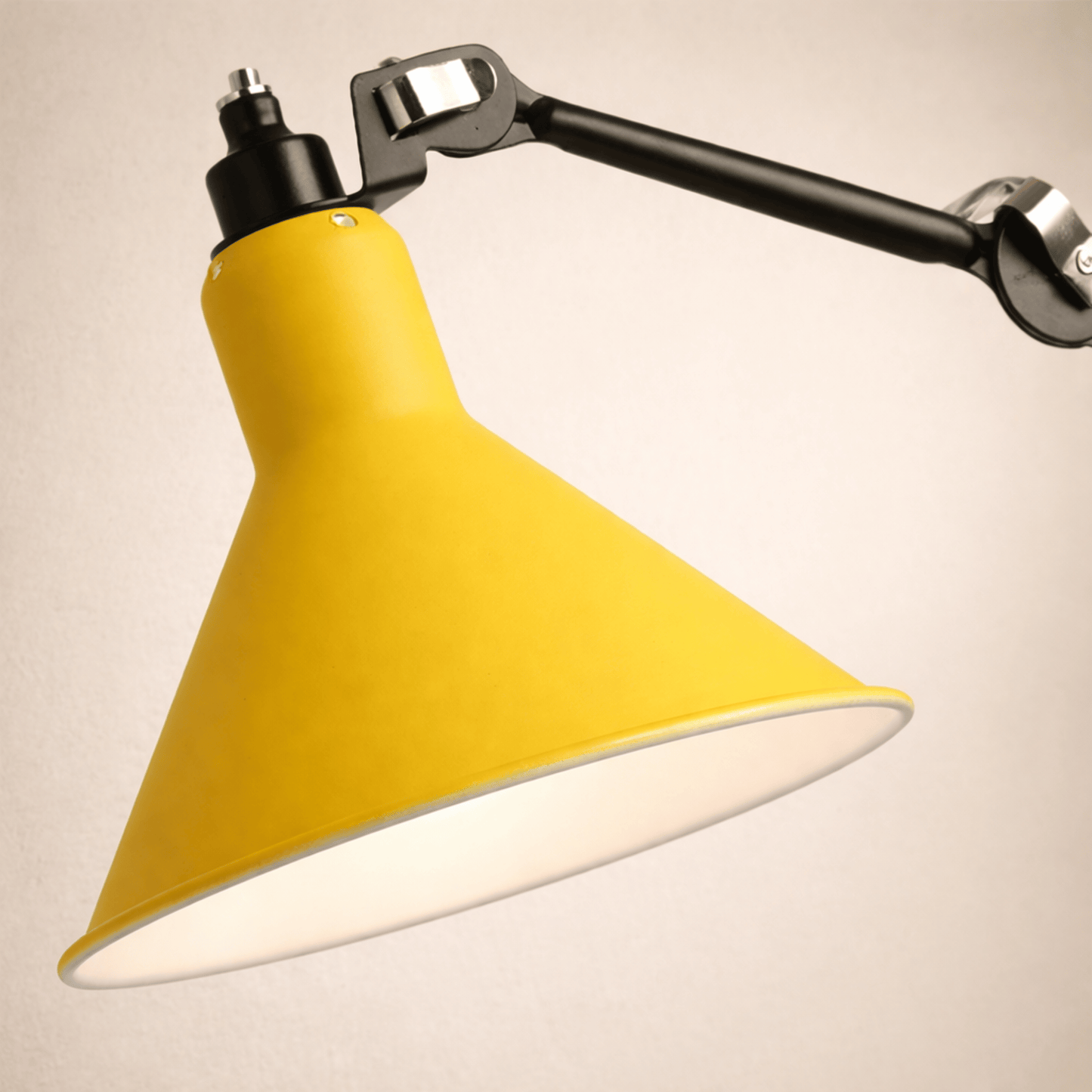 Yellow lampshade with a black adjustable arm on a beige background