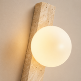 Wall-mounted light fixture with a spherical bulb on a neutral background
