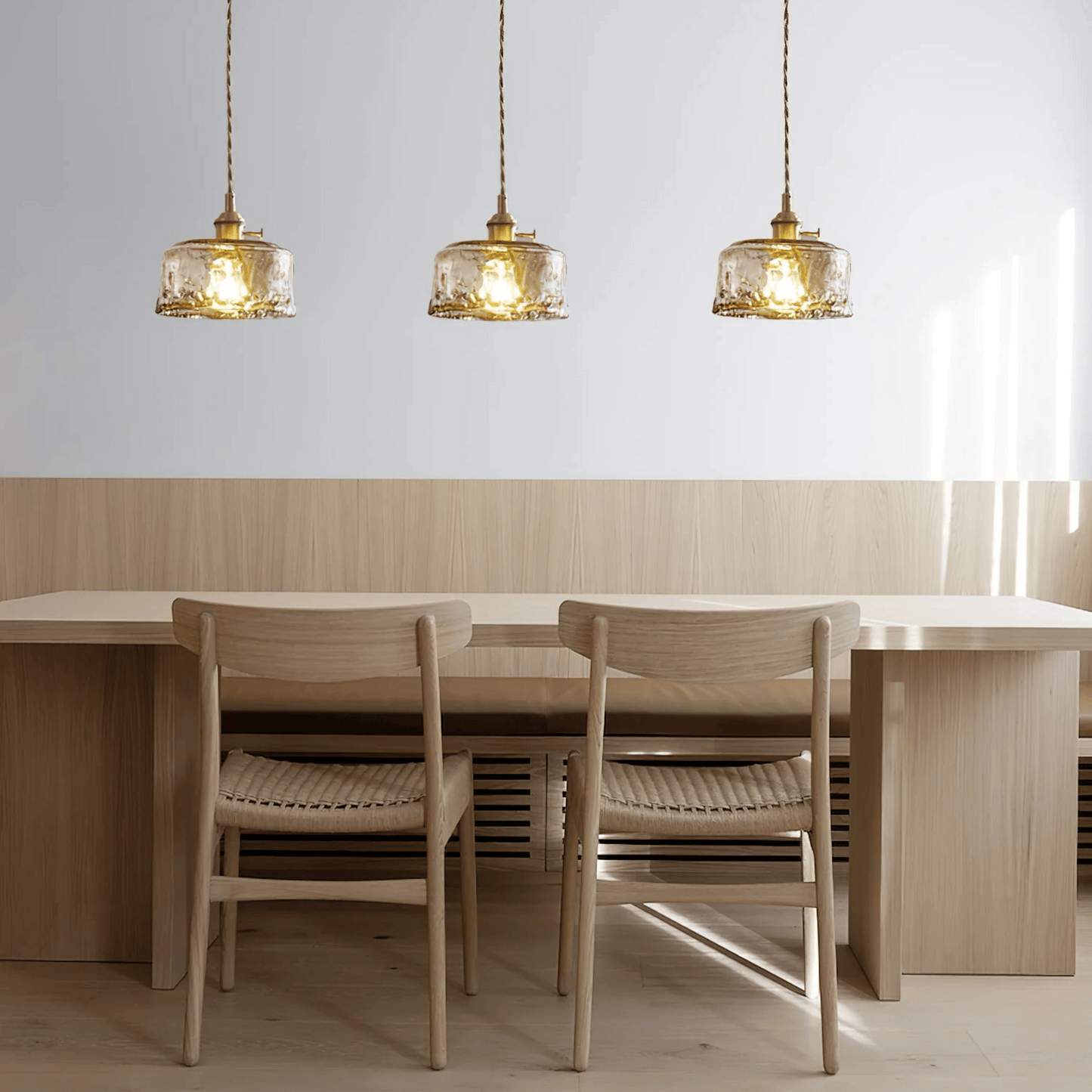 Dining area with wooden table and chairs under three pendant lights.