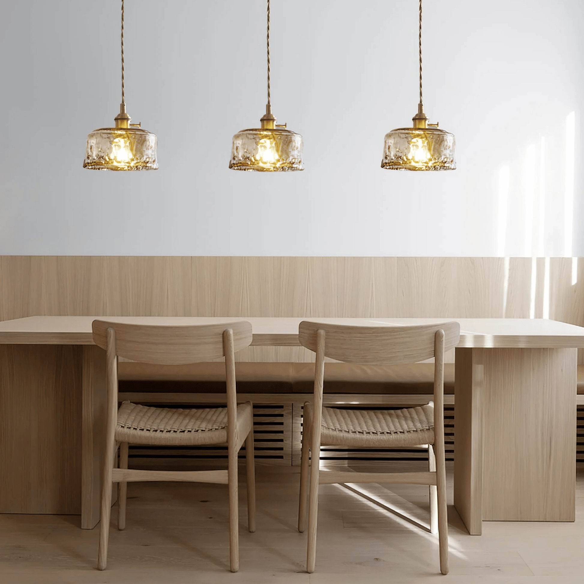 Dining area with wooden table and chairs under three pendant lights.