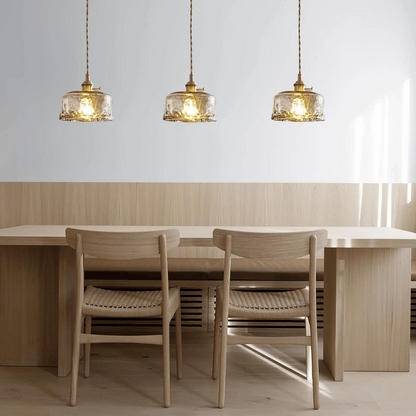 Dining area with wooden table and chairs under three pendant lights.