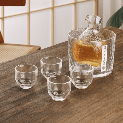 Clear glass decanter and cups on a wooden table with a blurred background