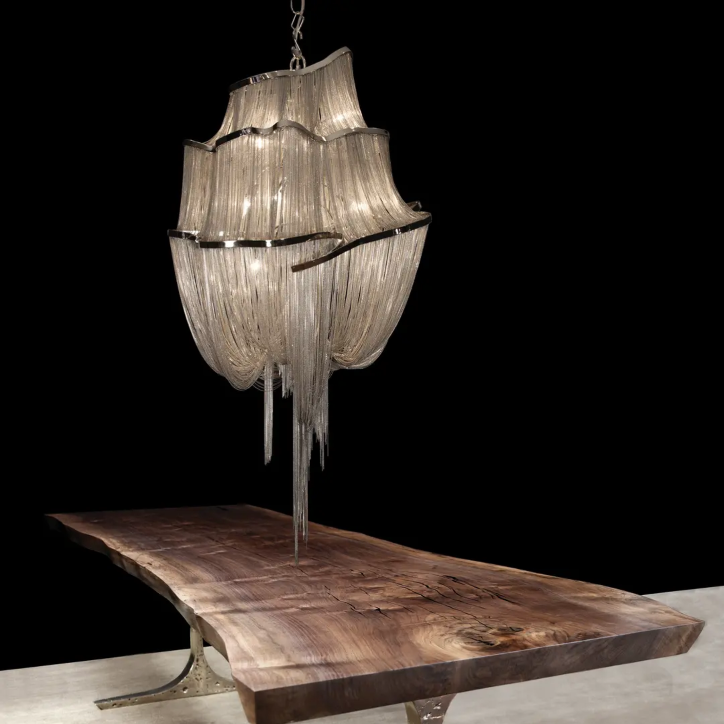 Decorative chandelier hanging above a wooden table with a black background