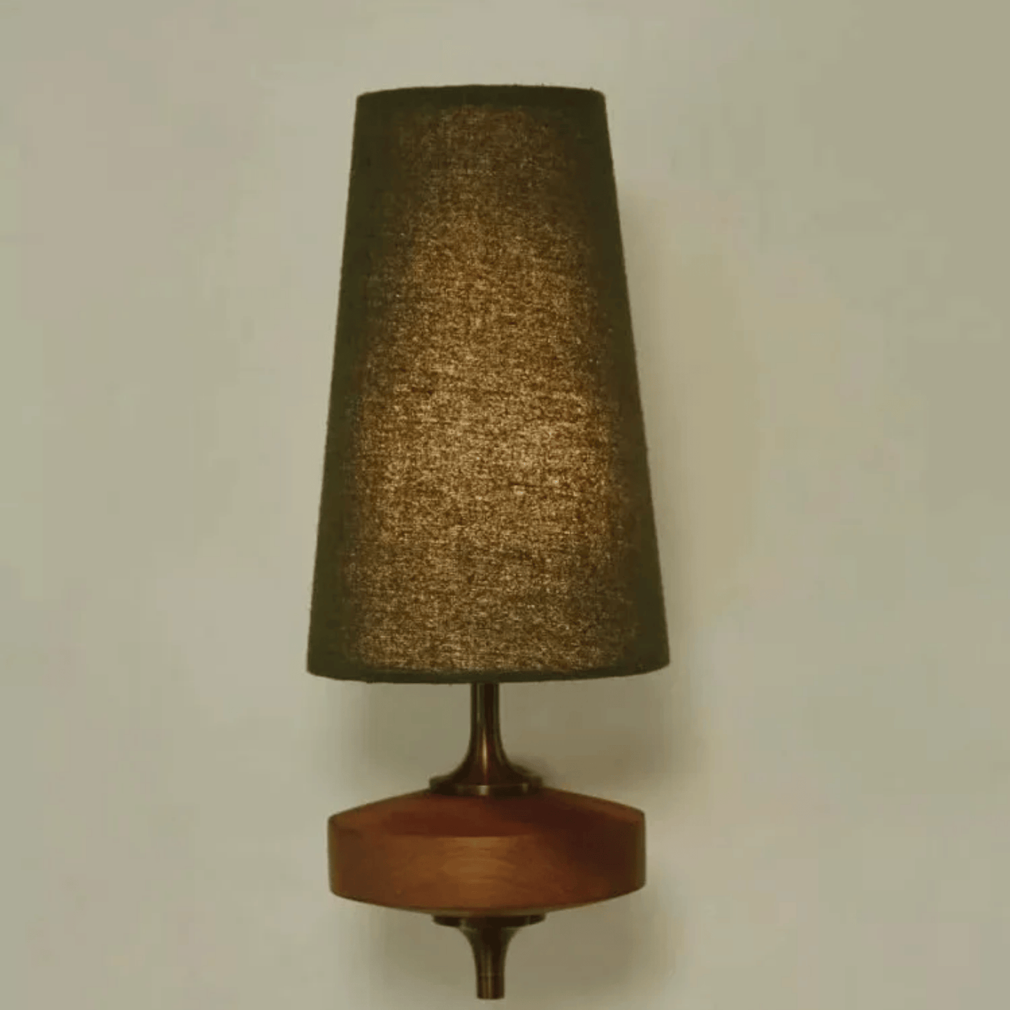 Wall-mounted lamp with a textured brown shade and wooden base on a plain wall.