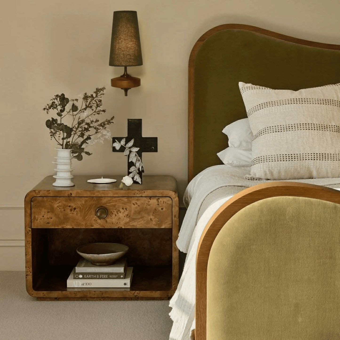 Bedroom with wooden nightstand, bed with pillows, and lamp.