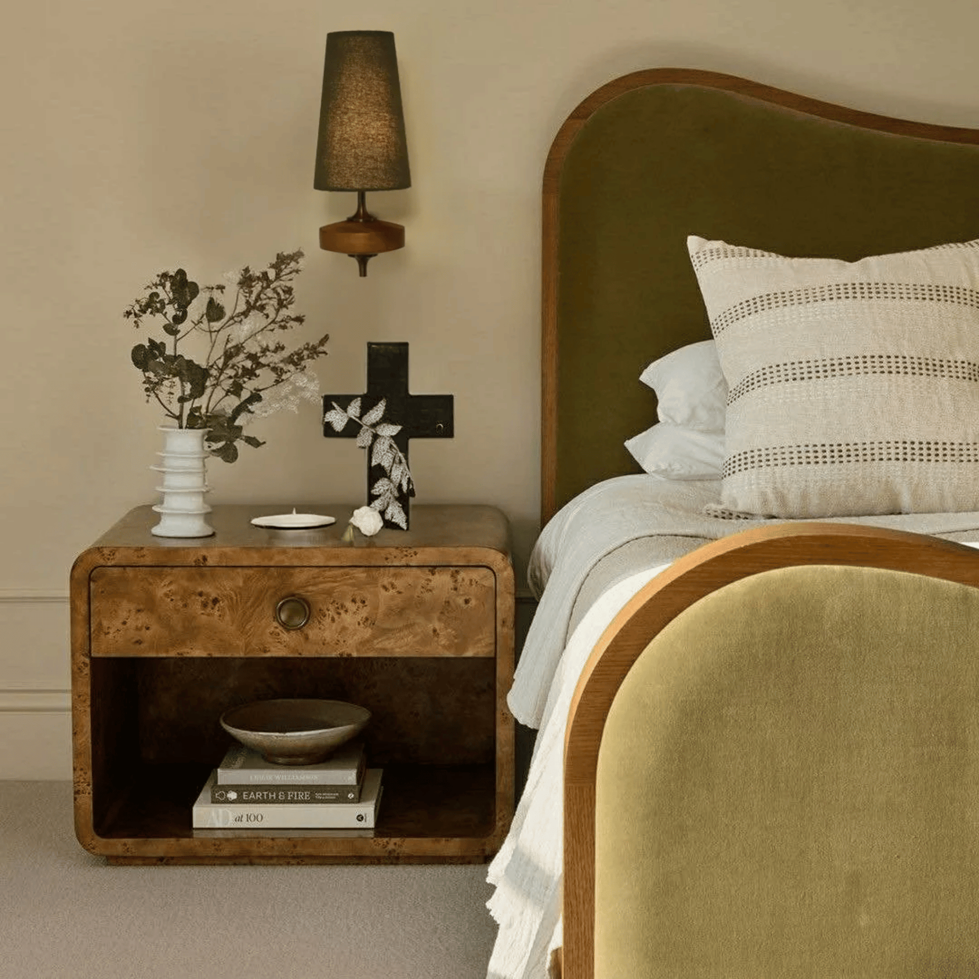 Bedroom with wooden nightstand, bed with pillows, and lamp.