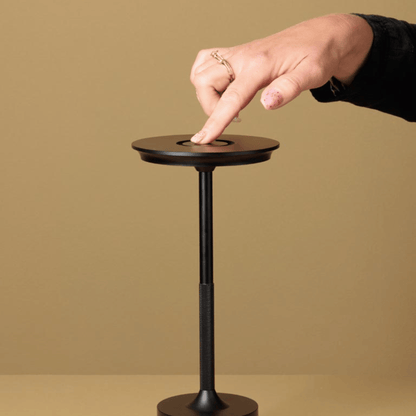 Hand pressing a button on a small round table against a beige background