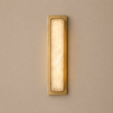 Rectangular wall light fixture with gold frame and glass cover on a beige wall.