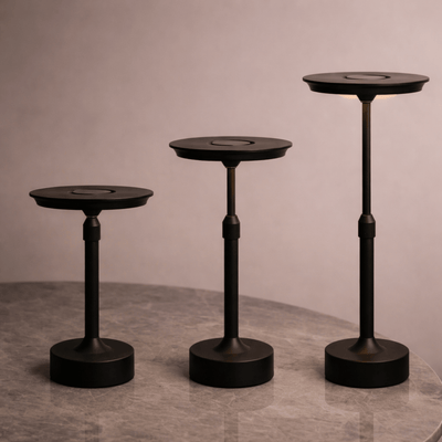Three black pedestal tables of varying heights on a gray surface with a neutral background