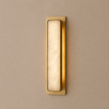Gold wall sconce with a beige light fixture on a beige wall