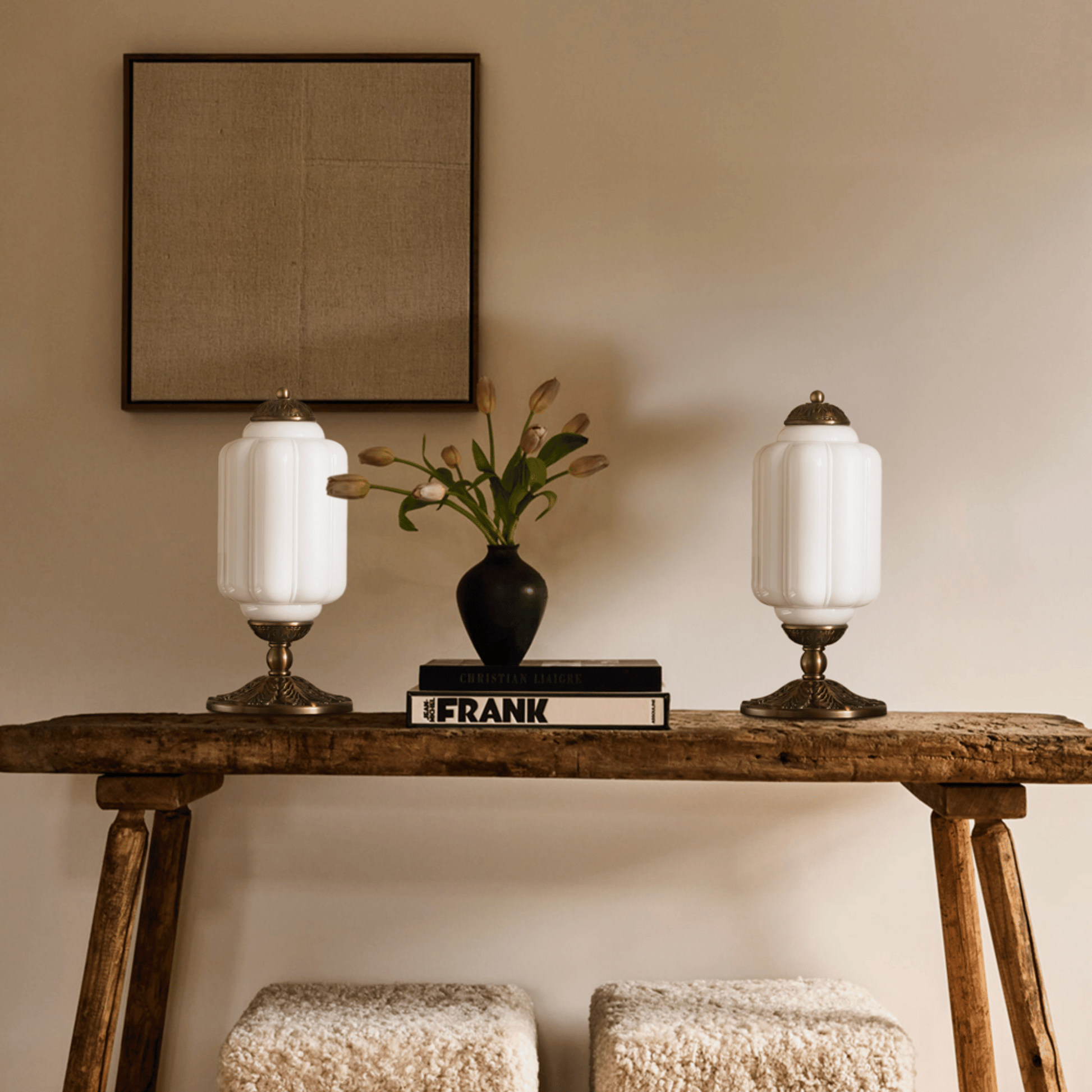 Wooden console table with two lamps and a vase on a beige wall background