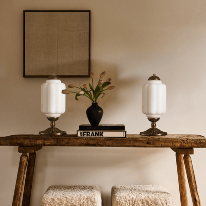 Wooden console table with two lamps and a vase on a beige wall background