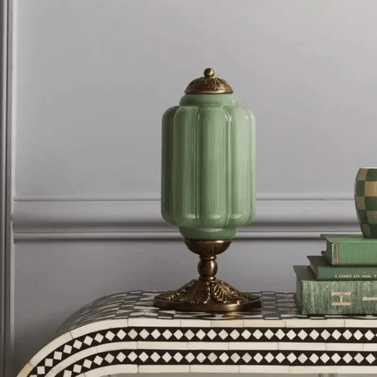 Green ceramic lamp with gold accents on a decorative table