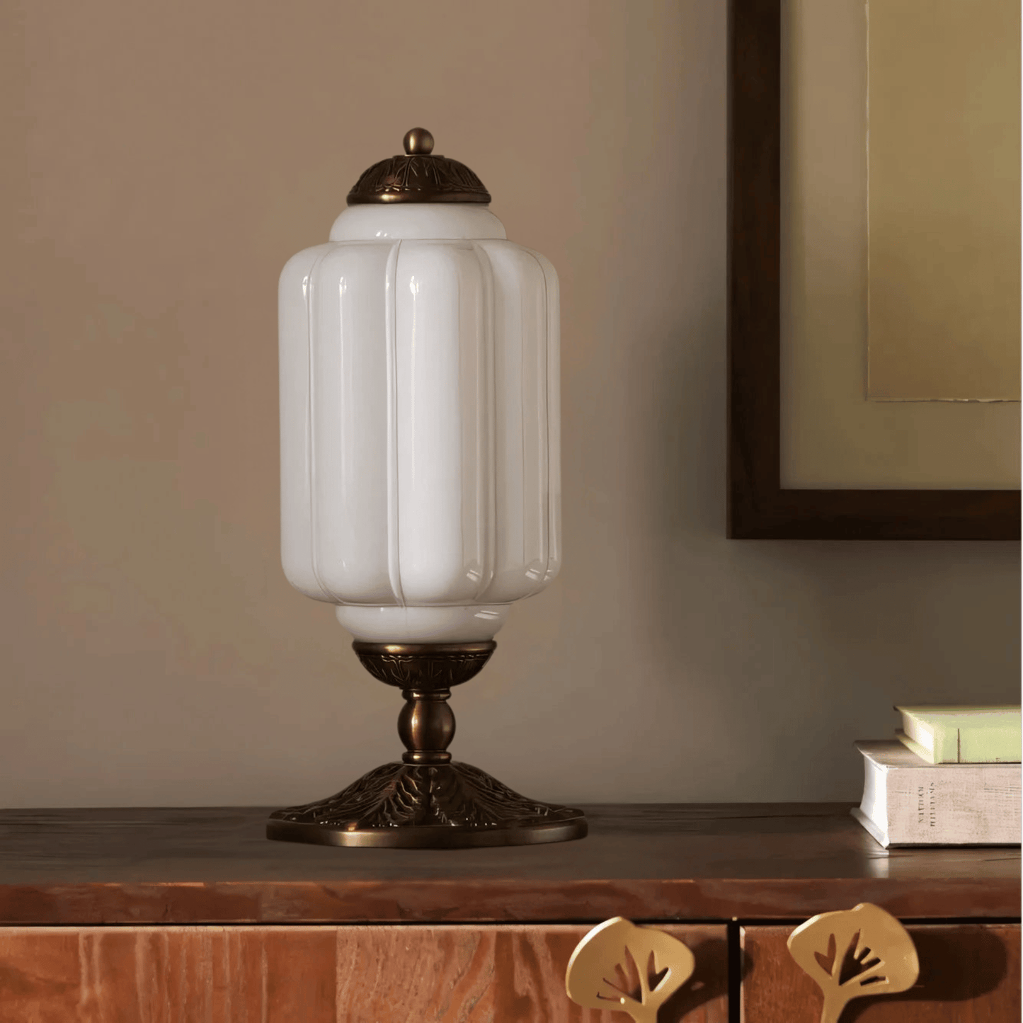 Decorative table lamp with white glass shade and bronze base on a wooden surface.