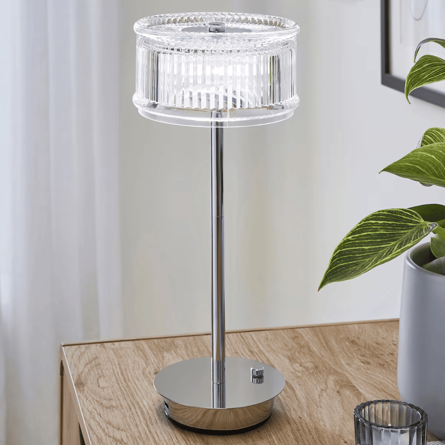 Modern table lamp with crystal design on a wooden surface next to a plant