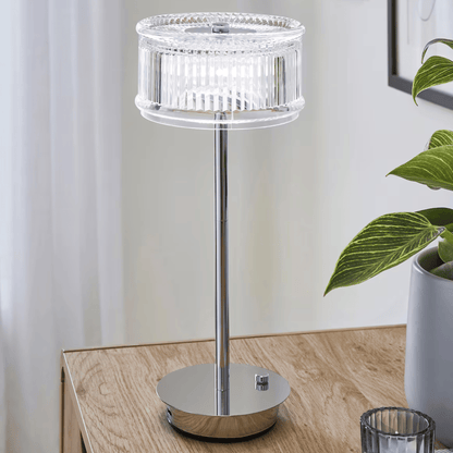 Modern table lamp with crystal design on a wooden surface next to a plant