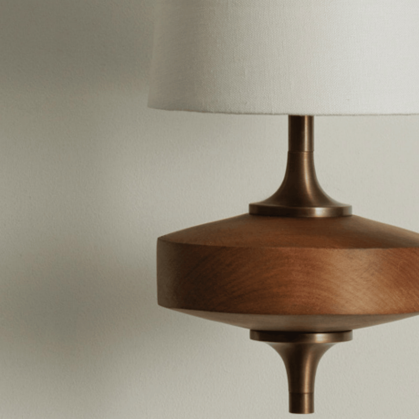 Close-up of a lamp with wooden base and beige shade on a neutral background