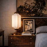 Decorative table lamp on a wooden nightstand next to a bed with a framed photo.