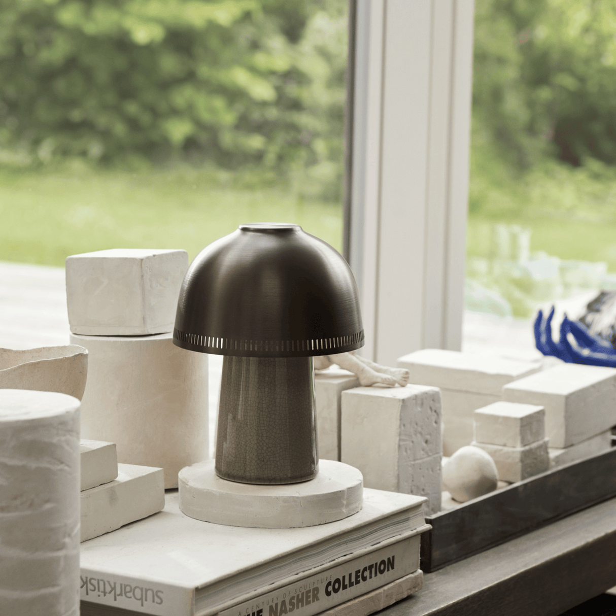 Decorative lamp on a surface with books and architectural models in the background