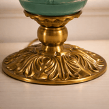 Decorative brass candle holder with a teal candle on a beige background
