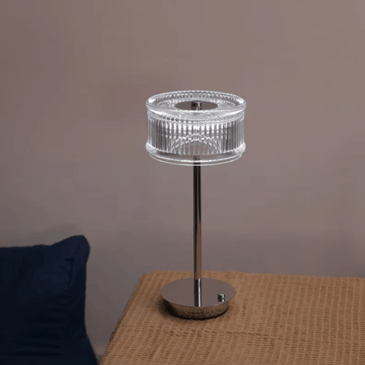 Modern table lamp with clear glass shade on a textured surface against a plain background