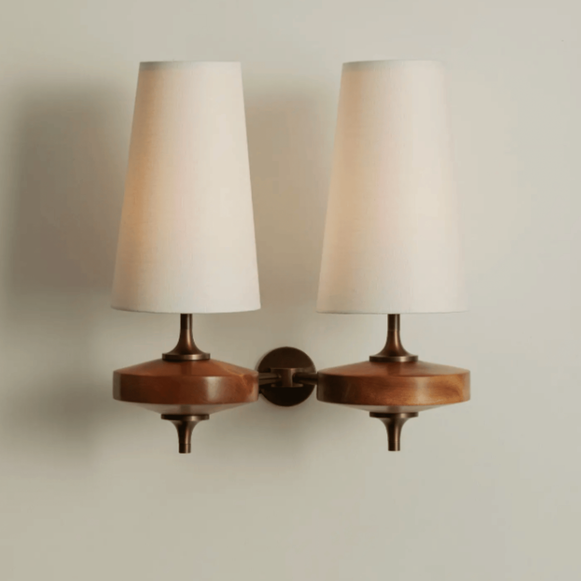 Pair of wall-mounted lamps with wooden bases and white lampshades on a neutral background
