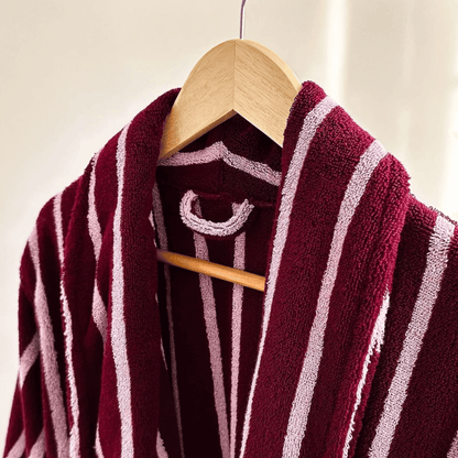 Maroon and white striped robe on a wooden hanger against a neutral background