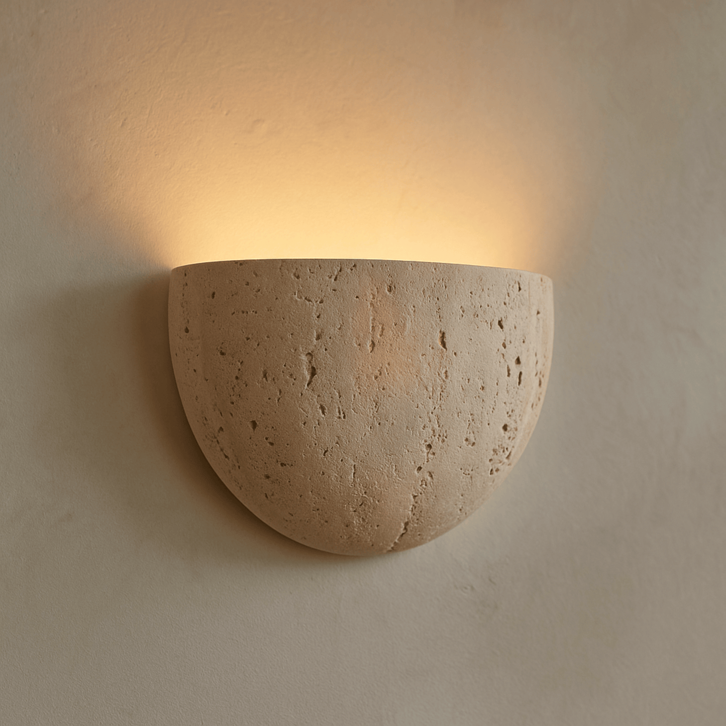Ceramic wall sconce emitting warm light on a beige wall