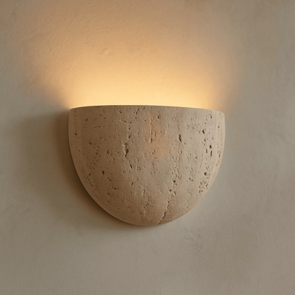 Ceramic wall sconce emitting warm light on a beige wall