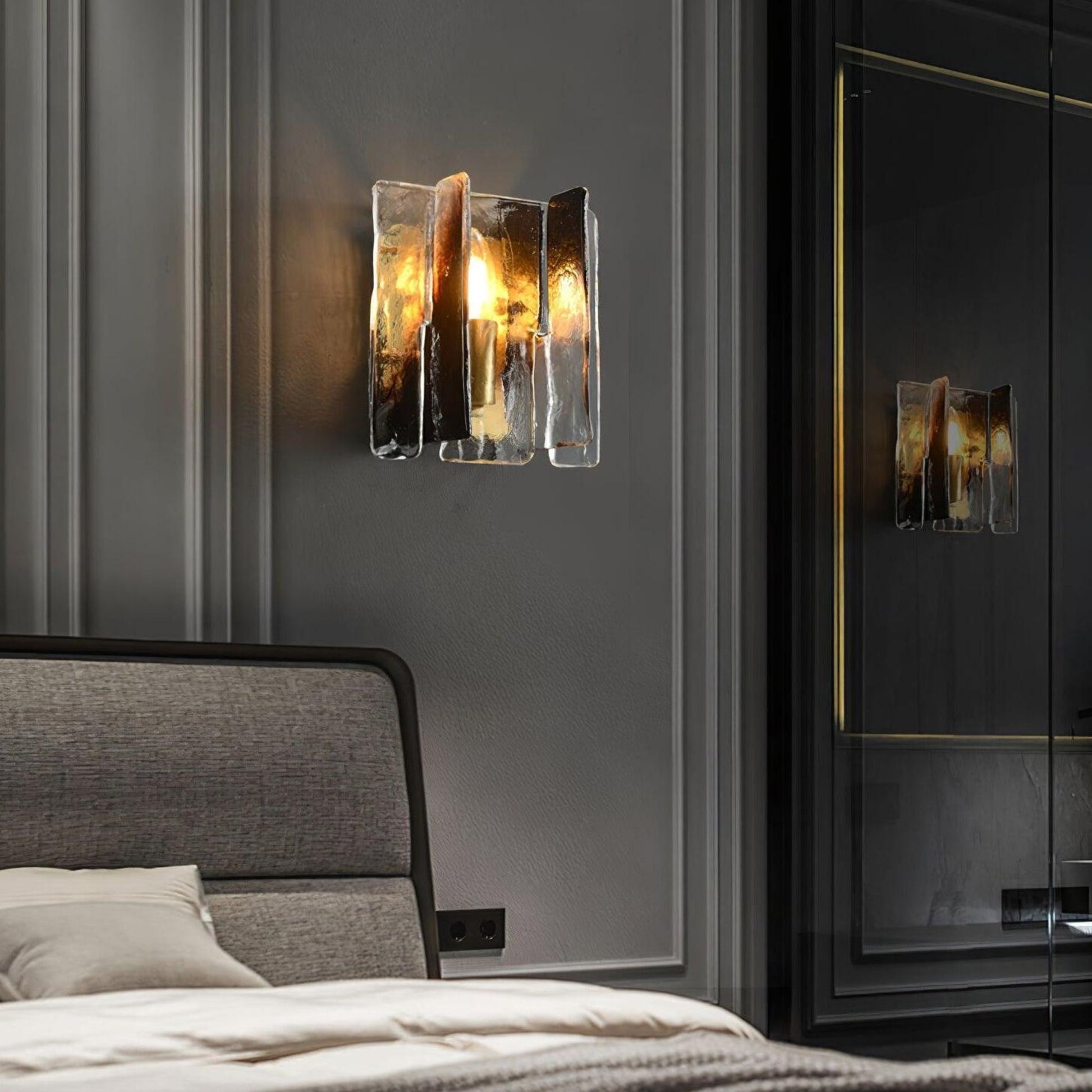 The glass wall sconce light mounted beside a bed, providing ambient light in a contemporary bedroom setup.