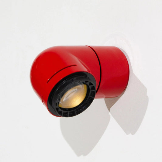 A person adjusting the red wall-mounted light fixture, showing its modern and functional design.