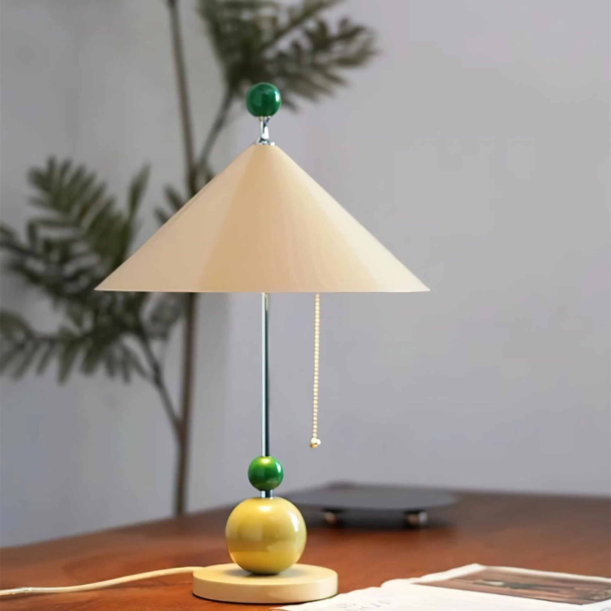 A close-up of the beige cone-shaped lampshade with a green accent ball and wooden base, casting soft light on the surface.