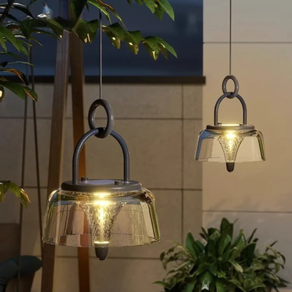 Two modern glass lanterns hanging outdoors, emitting a soft warm light.”