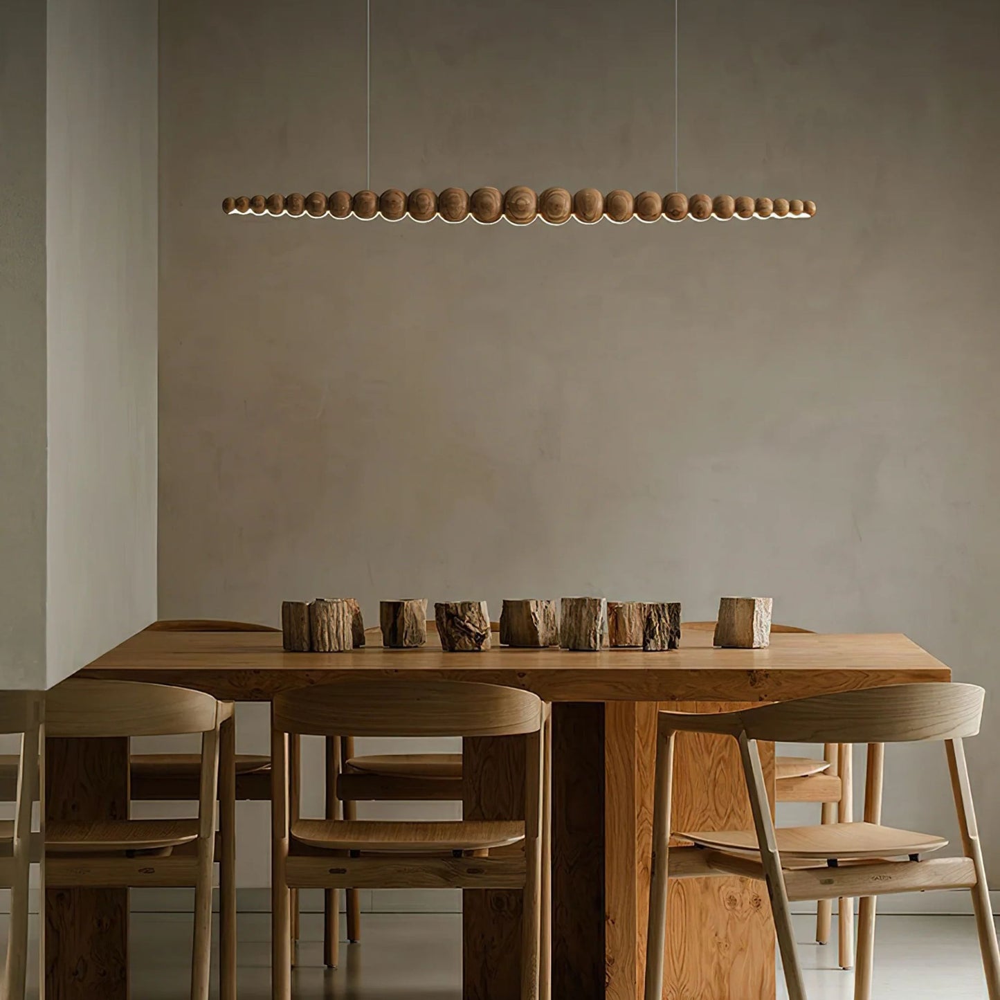 A minimalist dining area with a row of evenly spaced pendant lights above a wooden dining table.