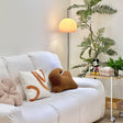 A yellow globe-shaped lamp in a living room, casting soft light near a bookshelf and creating a cozy ambiance.
