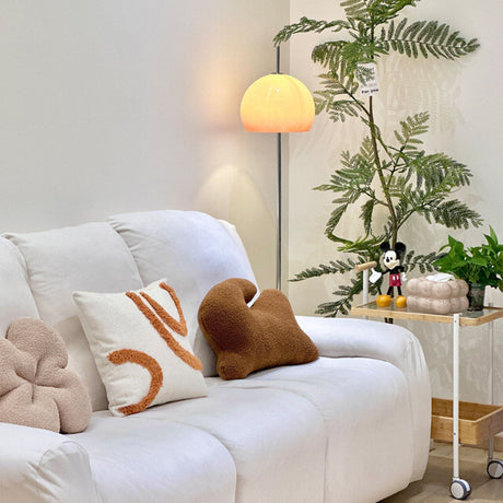 A yellow globe-shaped lamp in a living room, casting soft light near a bookshelf and creating a cozy ambiance.
