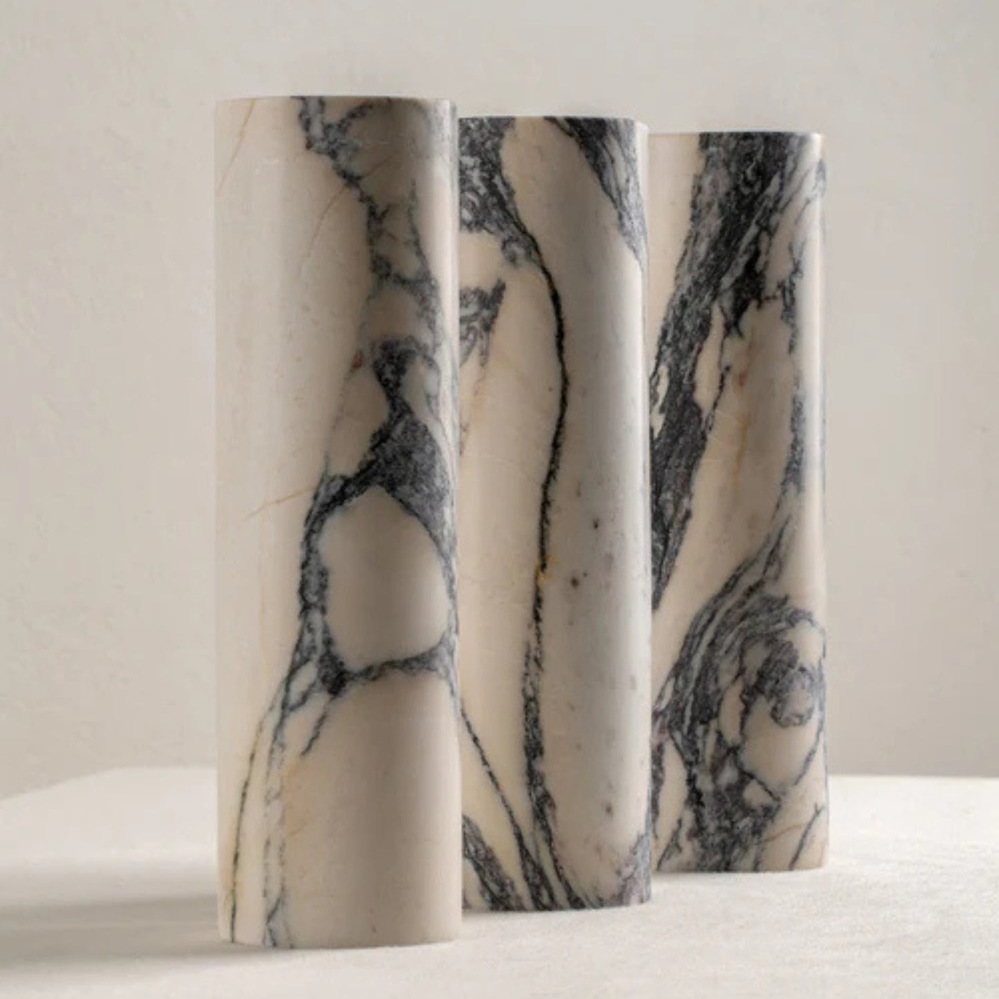 Pair of tall marble wall sconces mounted side by side on a beige wall.