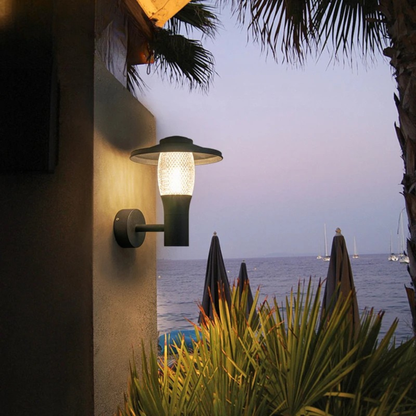 Modern outdoor sconce lighting up a tropical patio with sea view at dusk.