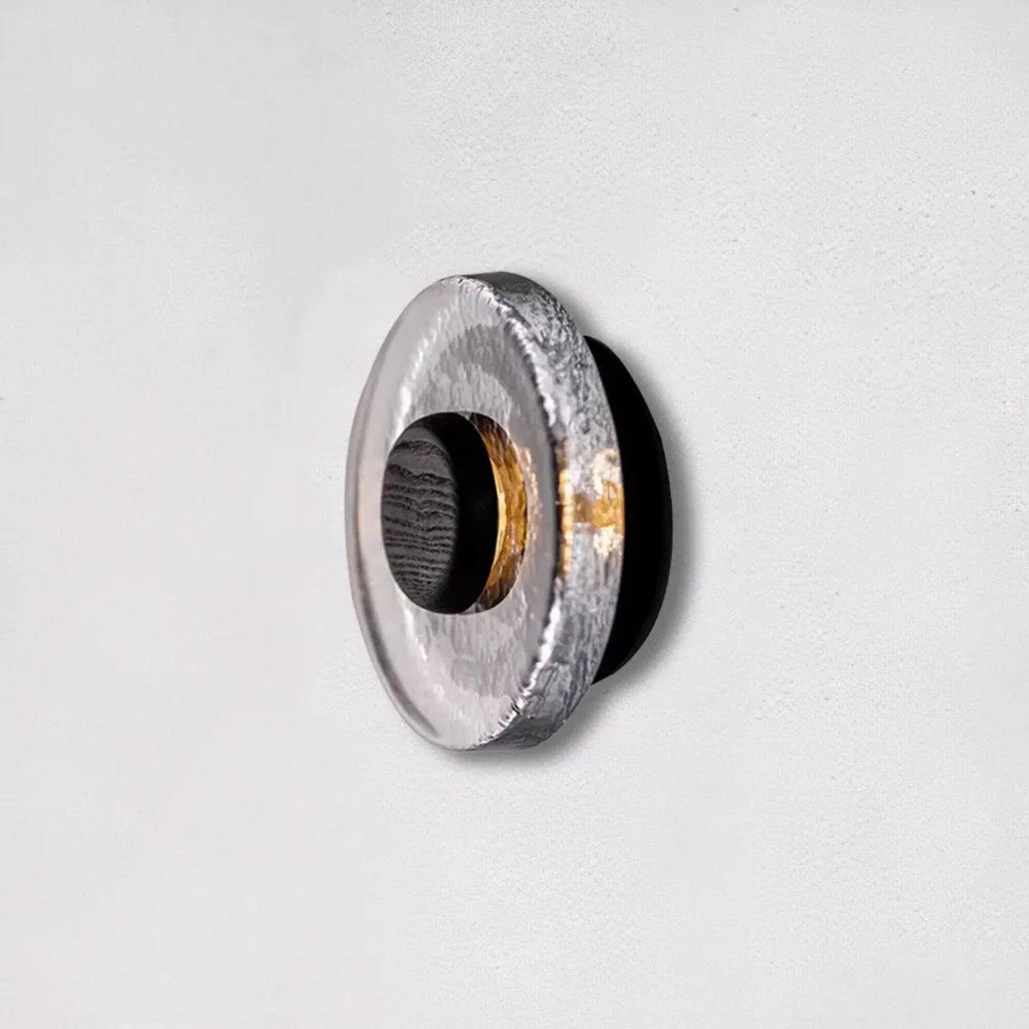 A close-up of the circular wall light showing the stone-textured surface and dark central core against a neutral background.