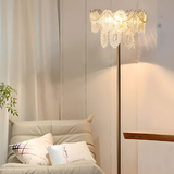 A close-up view of a chandelier-style lamp with delicate crystals, softly glowing in a well-lit room.