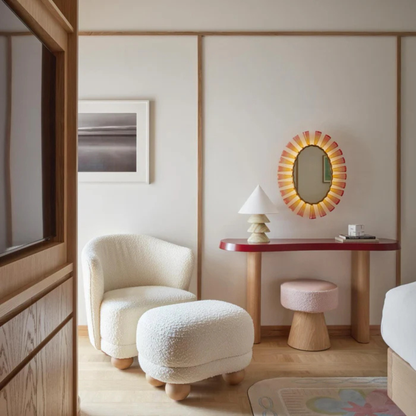 Modern room interior featuring a layered onyx table lamp on a red console table with a round sunburst mirror.