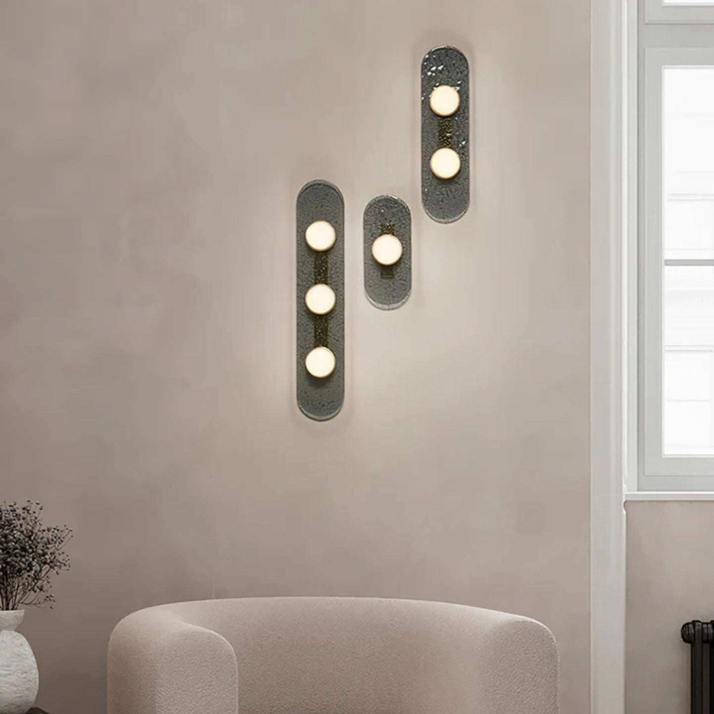 three bulb sconce viewed from the side mounted on a light grey wall