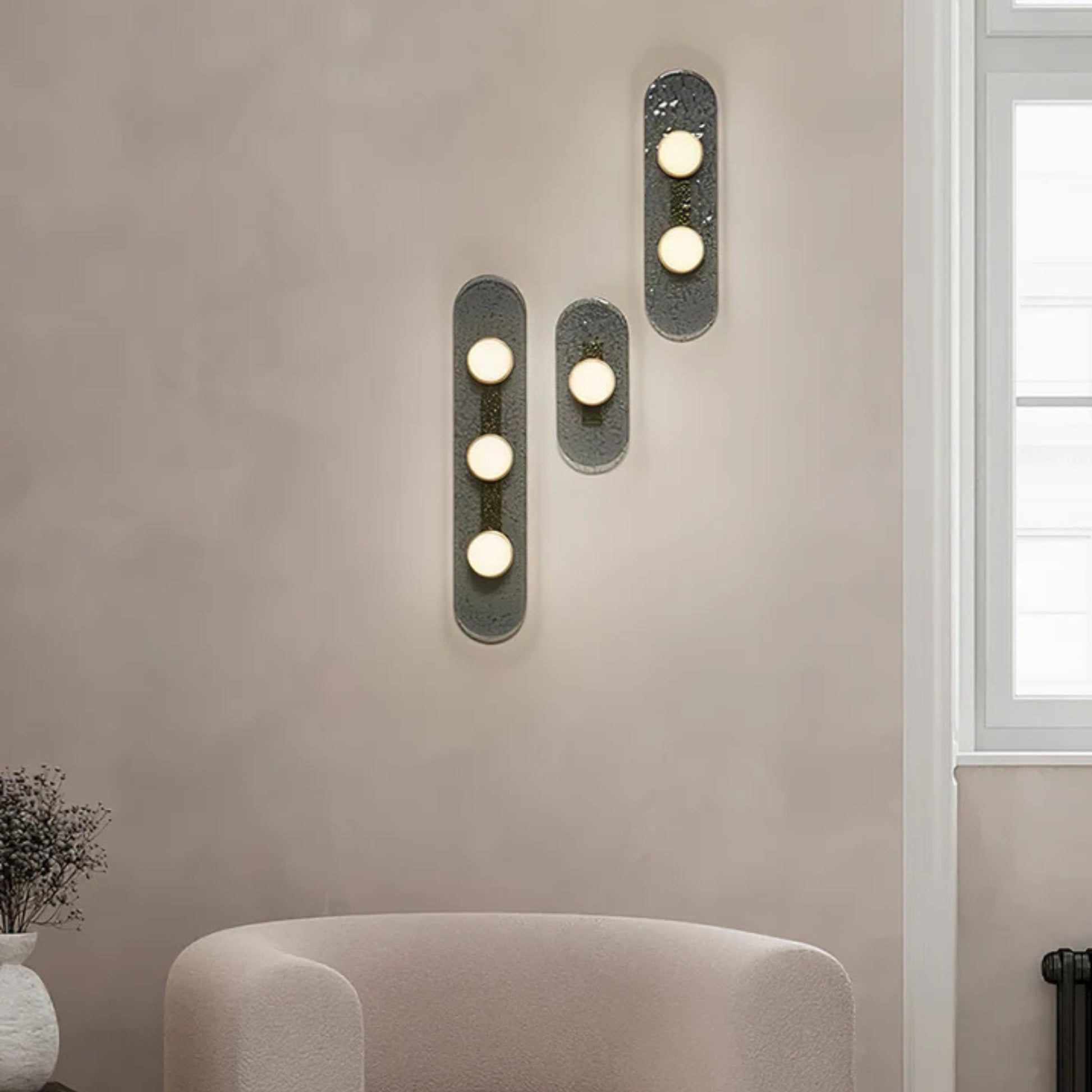three bulb sconce viewed from the side mounted on a light grey wall